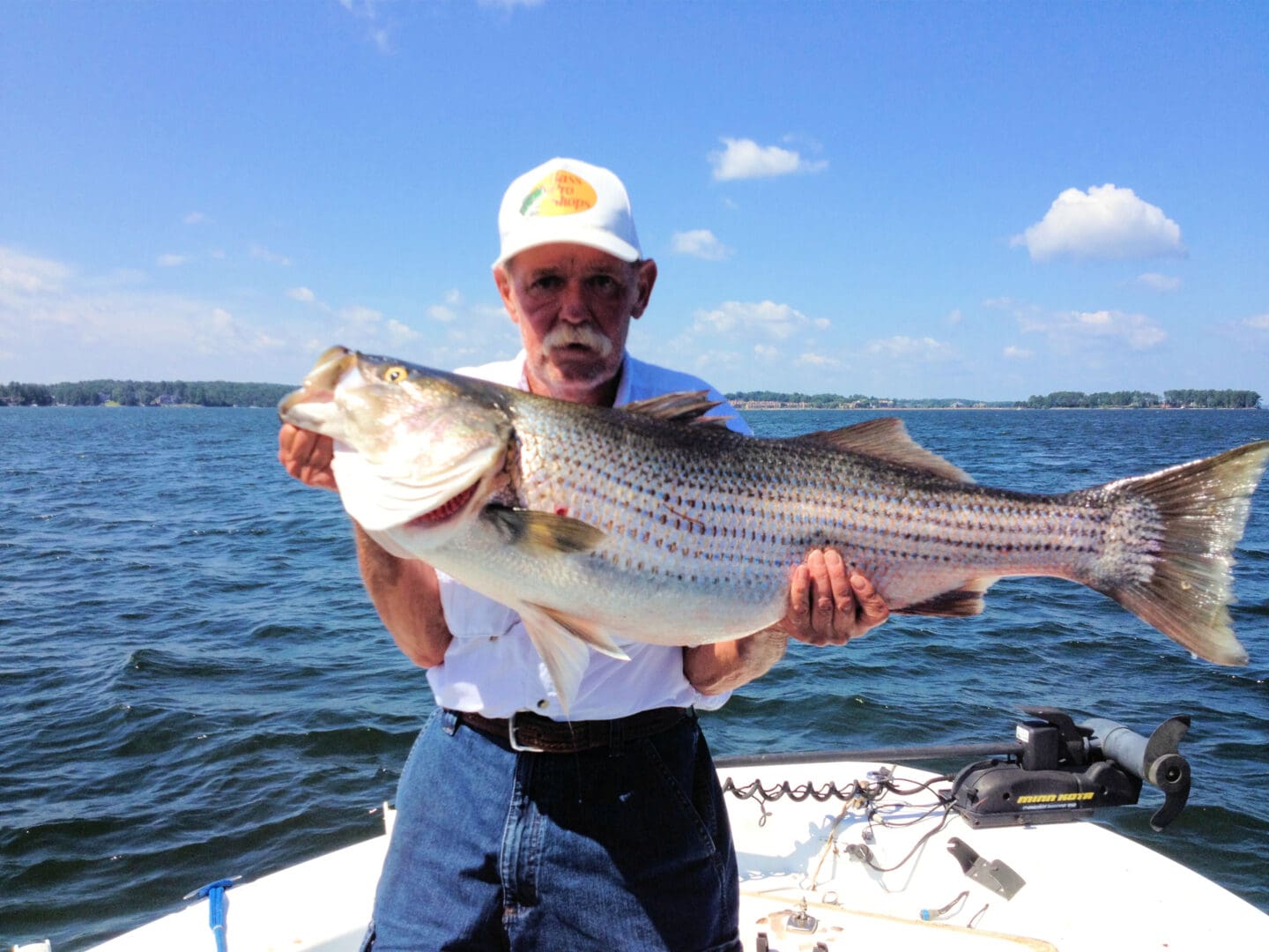 A man holding a large fish on top of a boat.